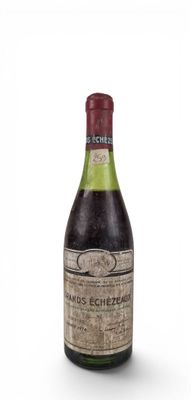 an old bottle of wine sitting on top of a white surface