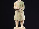 Une vieille statue représentant un homme muni d'une canne se dresse sur une surface noire.
