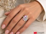 woman ' s hand with a pink manicured holding a ring with a purple flower on it