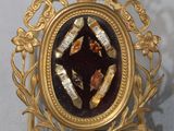 une image représentant un cadre doré dans lequel figure un homme coiffé d'une couronne