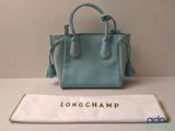 Le sac à main Longchamp est posé sur une table, à côté d'un autre sac.