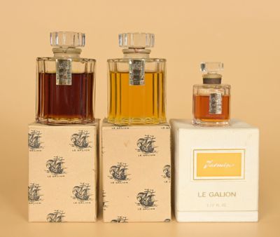 three bottles of perfume sitting on top of boxes next to each other
