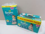 two boxes of baby diapers sitting on a table next to a box of diapers