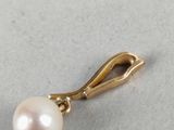 a close up of a pearl pendant on a white surface
