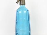 a blue glass bottle with a brass handle on a white background
