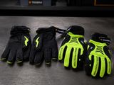 three pairs of black and yellow gloves sitting on top of a table