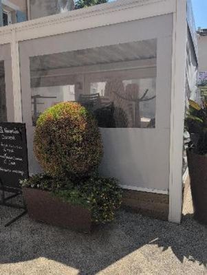 tables and chairs outside of a restaurant with a sign on the sidewalk