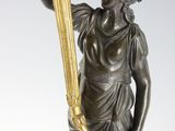 an antique bronze statue of a woman holding a torch in her hand