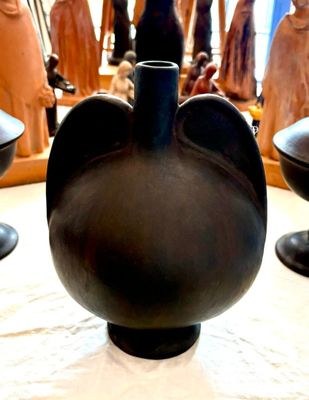 un vase noir posé sur une table, à côté d'autres vases noirs
