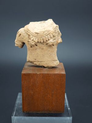 une statue ancienne représentant une tête posée sur un bloc de bois