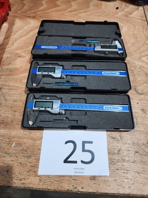 Trois pieds à coulisse sont posés sur une table sur laquelle est inscrit le chiffre 25.