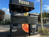 une pancarte indiquant « pizzas » au bord de la route