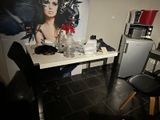 une pièce faiblement éclairée, avec une table, des chaises et un tableau accroché au mur