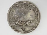 an old silver coin with a snake on it on a white surface