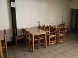 tables and chairs in a room with white walls and tile flooring