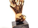 statue représentant une main dorée posée sur un socle en marbre noir