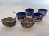 six bols en verre bleu et des cuillères posés sur une table blanche