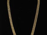 un collier à chaîne en or avec une pièce de monnaie sur fond noir