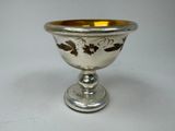 a silver cup with a gold rim on a white table