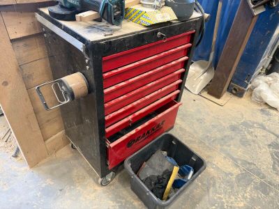 une boîte à outils rouge posée dans un garage, avec des outils dessus