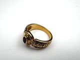 a close up of a gold ring with a red stone in it