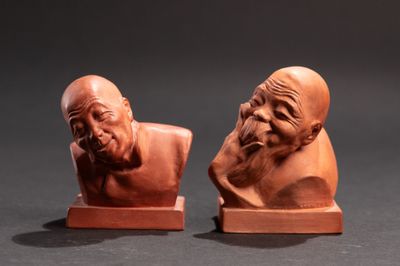 two clay busts of old men with beards sitting on wooden bases