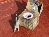une petite statue représentant un chat, posée à côté d'une boîte sur laquelle se trouve un bol