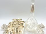 a silver tray with silver cups and a decanter on it