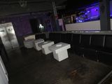 four toilets in the middle of a room with a bar in the background