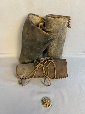 an old pair of boots and a leather bag on a white surface