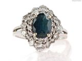 a close up of a diamond and sapphire ring on a white surface