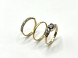three gold rings with diamonds on them on a white surface