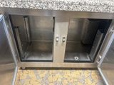a stainless steel cabinet with two doors open on a tiled floor