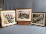 trois tableaux encadrés représentant des fleurs posées sur une table, sur fond bleu