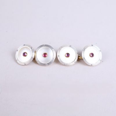 three silver and pink stone cufflinks on a white surface