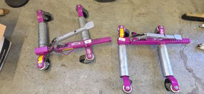 a pink scooter laying on the floor next to other scooters