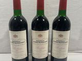 three bottles of red wine sit on a white surface