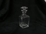 an empty glass bottle with a diamond shaped stopper on a black background