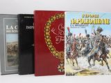 Trois livres sont posés sur une surface blanche ; l'un est rouge et l'autre est noir.