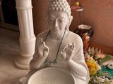 une statue de Bouddha assis par terre, avec un bol de nourriture devant lui