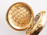 a close up of a gold pocket watch on a white surface