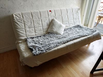 a white futon couch with pillows on it in a living room