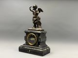une statue représentant un ange tenant une horloge posée sur une table
