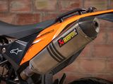 a close up of an orange motorcycle parked in front of a brick wall