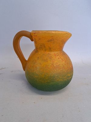 un vase jaune et vert posé sur une surface blanche