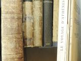 several old books are stacked on a shelf in a library