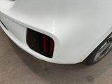 the rear end of a white sports car parked in a garage