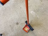 an orange pole that is on the floor next to a pair of shoes