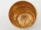 a glass with a liquid inside of it on a white surface
