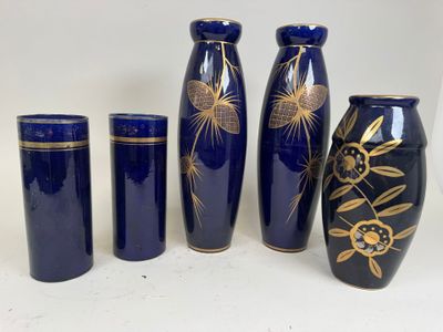 four blue vases with gold designs are lined up against a white background